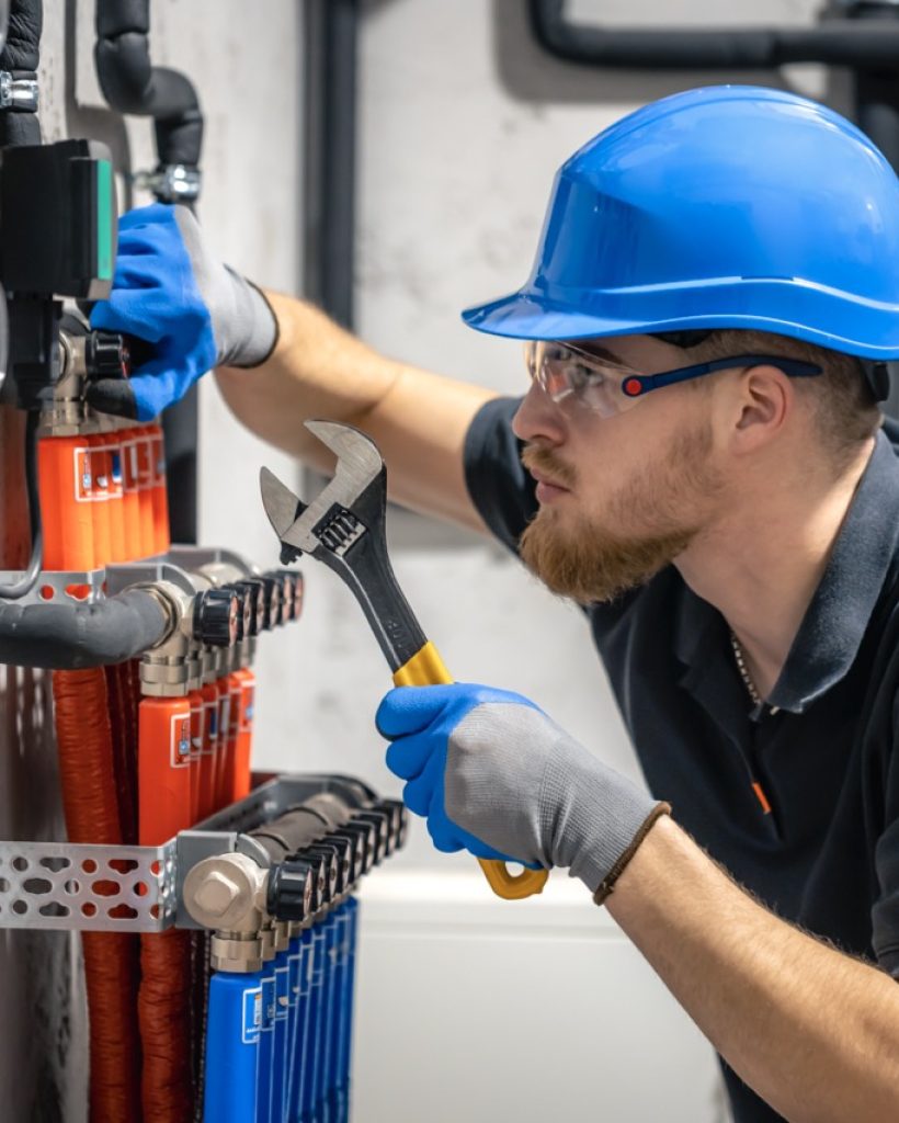 The technician checking the heating system in the boiler room. Adjusting heating valves in a residential building. A plumbing and heating technician works.